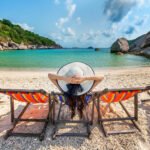 woman with hat sitting chairs beach beautiful
