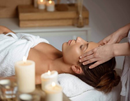 young woman having face massage relaxing spa salon