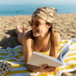 full shot woman reading book beach