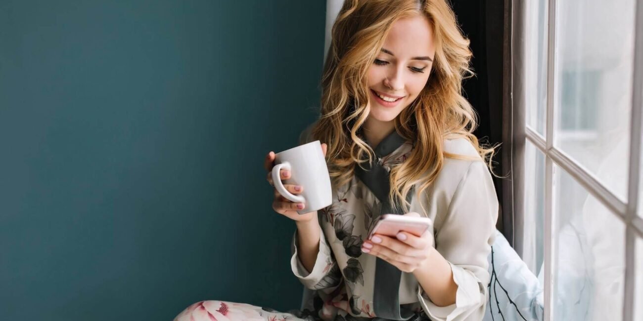 pretty blonde girl sitting window sill with cup